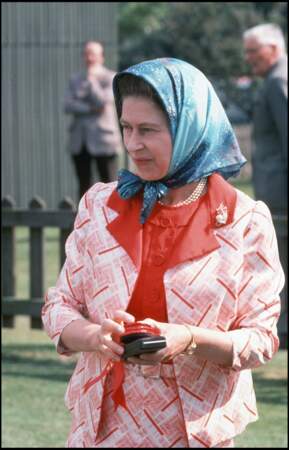 La reine Elizabeth II a fait le pari de décaler sa tenue rose et rouge avec un foulard bleu turquoise, en 1976.