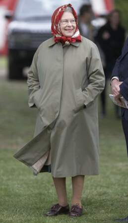 Pour pimper son imperméable vert kaki, la reine Elizabeth II a noué autour de sa tête un carré de soie rouge cerise lors du Royal Windsor Horse Show, le 14 mai 2010.