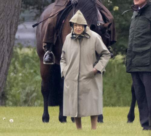 Pour rendre visite aux chevaux du prince Philip, la reine Elizabeth II a enfilé son intemporel imperméable et noué un foulard de soie noir, le 30 avril 2021.