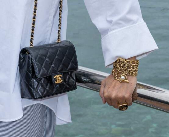 Carole Bouquet sélectionne un sac en cuir lisse Chanel au défilé croisière Chanel à Monaco, le 5 mai 2022. 