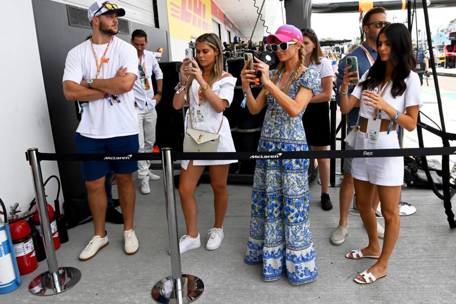 Paris Hilton et sa robe longue et fleurie lors du Grand Prix de Formule 1 de Miami, le 8 mai 2022. Elle accessoirise sont look d'une imposante paire de lunettes blanches ainsi qu'une casquette rose, la couleur tendance de ce printemps/été 2022 