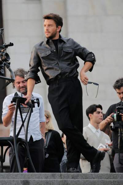 L'acteur Jonathan Bailey porte une surchemise en cuir conjuguée à un pantalon de costume noir au défilé de mode Hommes printemps-été "AMI" au Sacré Coeur à Paris.
