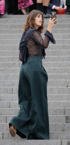 Jeanne Damas craque pour un pantalon large vert émeraude et blouse en tulle et noire au défilé  de mode Hommes printemps-été "AMI" au Sacré Coeur à Paris. 