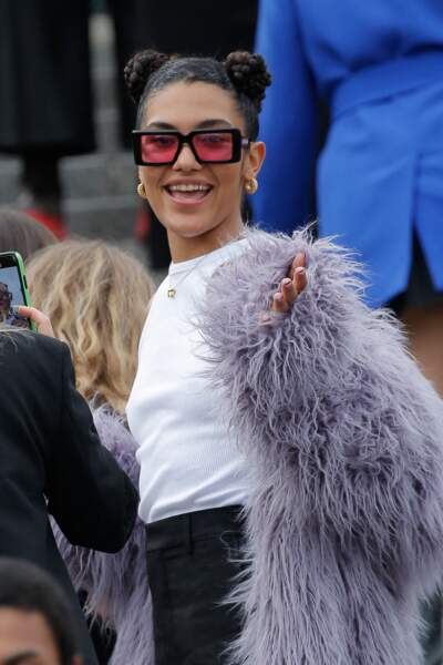 La chanteuse Olivia Dean mise sur un top blanc et une veste à plumes au défilé de mode Hommes printemps-été "AMI" au Sacré Coeur à Paris.