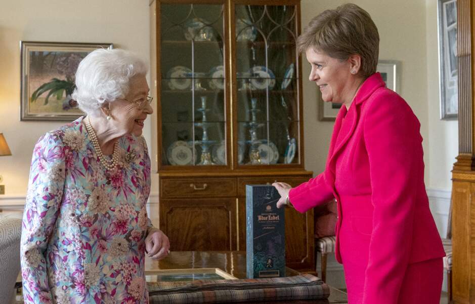 La reine Elizabeth II reçoit une bouteille de whisky en cadeau par la Première ministre d'Écosse Nicola Sturgeon, le 29 juin 2022.