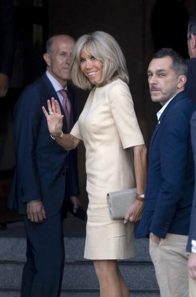 La Première Dame française, Brigitte Macron en top blanc immaculé et pantalon blanc rayé avec des escarpins marrons.