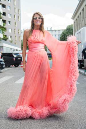 Anna Dello Russo, la journaliste spécialisée dans la mode craque pour une robe corail à plumes pour le défilé Haute Couture Alexandre Vauthier - collection automne-hiver 2022-2023, le 5 juillet 2022