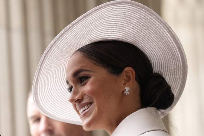 Meghan s'habille d'un total-look blanc Dior et craque naturellement pour un ultra-chic chignon bas roulé soigneusement coiffé sur un côté sous son élégant chapeau blanc, le 3 juin 2022.