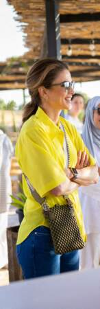 Rania de Jordanie accessoirise sa tenue d'un mini-sac en bandoulière de la marque Tissa Fontaneda London - disponible dès 695€ - ainsi qu'une paire de lunettes de soleil Olivier Peoples x Frère, le 14 août 2022.