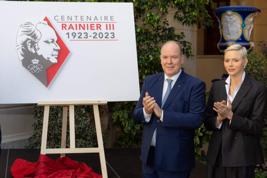 Le prince Albert II de Monaco et son épouse la princesse Charlene posent tout sourire aux côtés du logo choisi pour les célébrations du centenaire du prince Rainier III, au Palais de Monaco, le 28 septembre 2022.