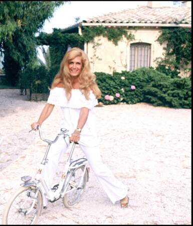 Dalida lumineuse dans un total look blanc en pantalon flare et blouse au décolleté Bardot à Saint Stropez, le 12 juillet 1978
