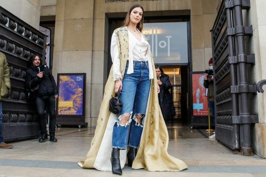 En reine de la mode dans cette tenue composée d'un jean à trous, d'une blouse blanche et d'un manteau-cape pour le défilé Stéphane Rolland Haute-Couture 2022 au palais de Chaillot en janvier 2022