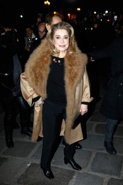 Pour affronter le froid, Catherine Deneuve se recouvre d'un manteau en fausse fourrure beige au défilé Jean Paul Gaultier - FW Haute Couture, printemps/été 2023 - à Paris, le 25 janvier 2023 