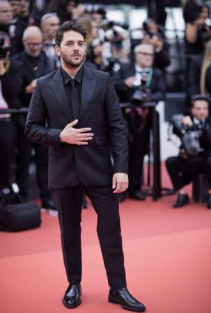 Xavier Dolan simple mais chic dans un costume noir signé AMI et paré d'une montre et d'une bague Serpenti Viper Bulgari - Montée des marches du film 'Jeanne du Barry' pour la cérémonie d’ouverture du 76ème Festival de Cannes