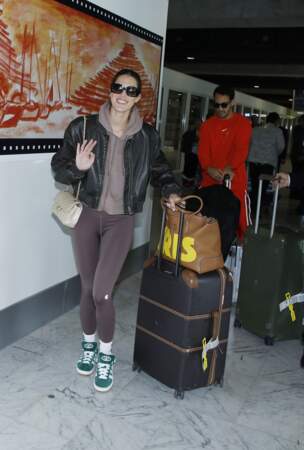 Iris Mittenaere en leggings et hoodie, avec un sac Chanel Timeless écru et un cabas Gucci à son nom. 