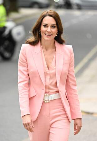 Kate Middleton portant un tailleur pantalon à l'apparence classique, mais dont le rose dragée a rendu le look pétillant et stylé.