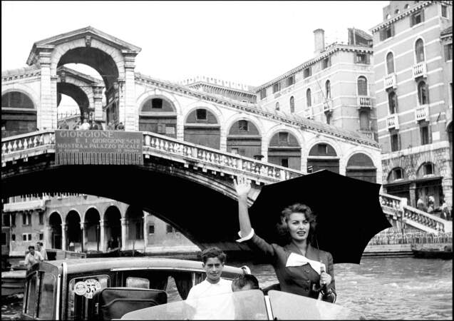 Sofia Loren salue les photographes de son bateau sur le Grand Canal,  en 1955.