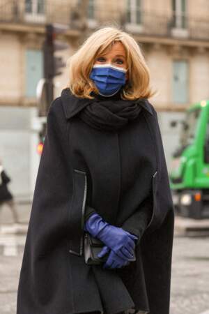Brigitte Macron chic et élégante en manteau cape noir, gants et masques bleus assortis pour l'hommage à Pierre Cardin, le 29 janvier 2021