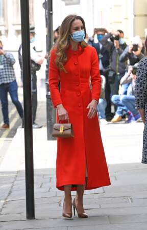 Kate Middleton, duchesse de Cambridge, dans son long manteau rouge et un sac à main en cuir DeMellier, le 7 mai 2021, pour la sortie de son livre.