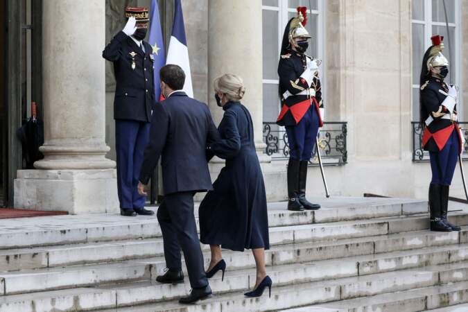 Exit ses robes graphiques ou ses manteaux en tweed, Brigitte Macron a cette fois misé sur un look plus solennel, en choisissant de porter une longue robe bleu marine. 
