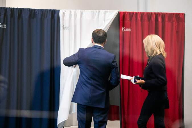 Le président de la république Emmanuel Macron ouvre le rideau à la Première dame, qui s'apprête à voter.