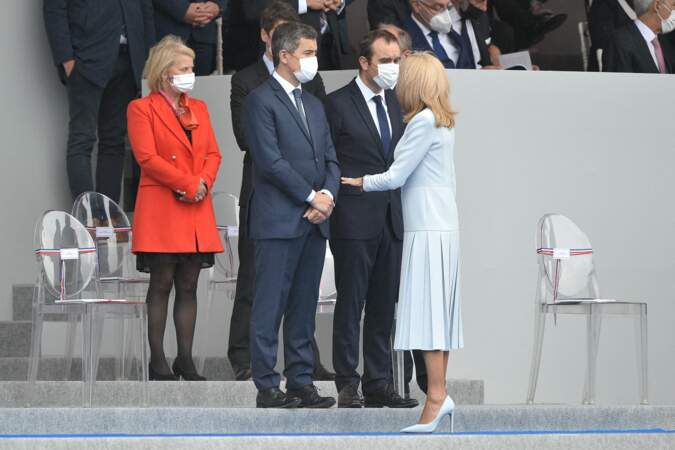 Avant de s'installer au côté du président de la République, Brigitte Macron a pris le temps de saluer les ministres présents, à l'instar de Gérald Darmanin, le 14 juillet 2021.