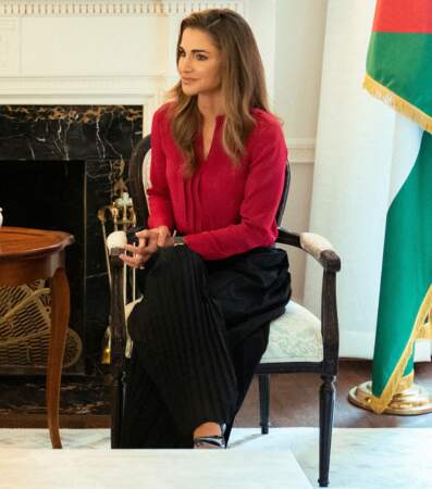 Rania de Jordanie portait un chemisier écarlate avec un pantalon fluide noir.
