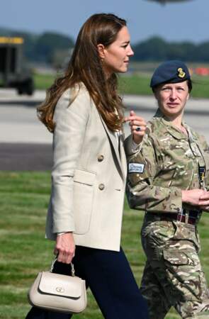 Kate Middleton porte un pantalon large bleu, une veste de blazer de la marque Reiss et un sac à mains Tusting