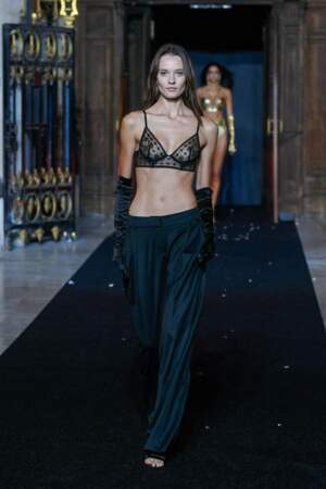 Alicja Tubilewicz porte un soutien-gorge triangle noir sur pantalon large et gants Opéra au défilé Etam 2021