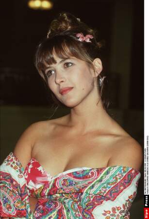Sophie Marceau en robe de jeune première à imprimés orientaux, fleur tropicale dans les cheveux en 1991