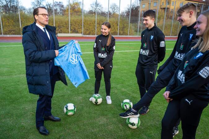 Le prince de Suède tenant le maillot de l'équipe de football de Malmö entouré de jeunes joueurs le vendredi 26 novembre.