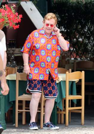 Elton John, en short et chemise orange à imprimé très 70's, lors de vacances en Italie en juillet 2021