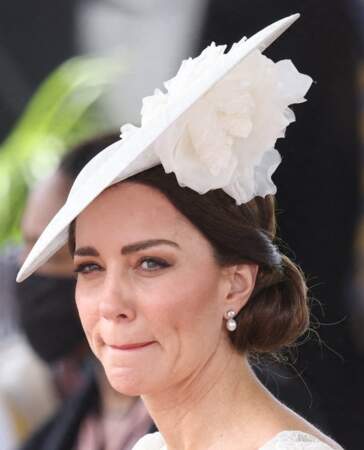 Accesoirisé d'un chapeau, le chignon bas de Kate Middleton est élégant. Une coiffure adoptée lors de la parade des officiers de l'Académie militaire des Caraïbes, à Kingston, le 24 mars 2022. 
