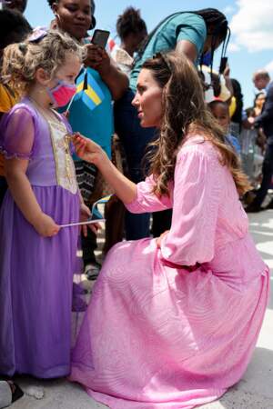 Kate Middleton toute vêtue de rose face à une petite fille dans une robe violette 