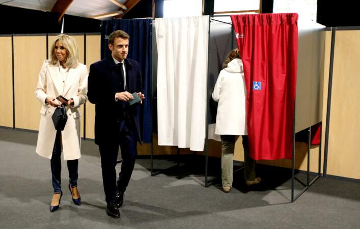 Blue jean, escarpins vernis bleu marine, manteau immaculé jouant sur des effets de symétrie et  sac à main version miniature pour Brigitte Macron au Touquet le 10 avril 2022.