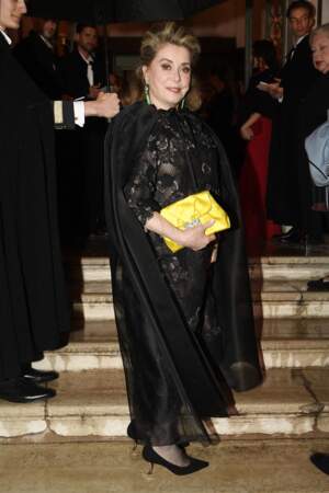 Adepte du style rock'n glam', Catherine Deneuve a décalé sa robe en dentelle noire avec une pochette satinée jaune tournesol, lors du dîner de gala organisé par Dior dans le cadre de la 59 ème Biennale d'art de Venise, le samedi 23 avril 2022.