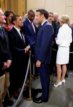 Pour accessoiriser son look monochrome, l’épouse du président de la République a sélectionné des escarpins blancs avec un détail argenté sur le devant, un rappel avec sa veste de tailleur