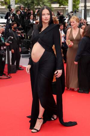 Adriana Lima enceinte monte les marches du film « Top Gun : Maverick » lors du 75ème Festival  de Cannes. La mannequin américaine d'origine brésilienne porte une robe à épaulettes et dénudée au niveau du ventre signée Balmain, le 18 mai 2022. 