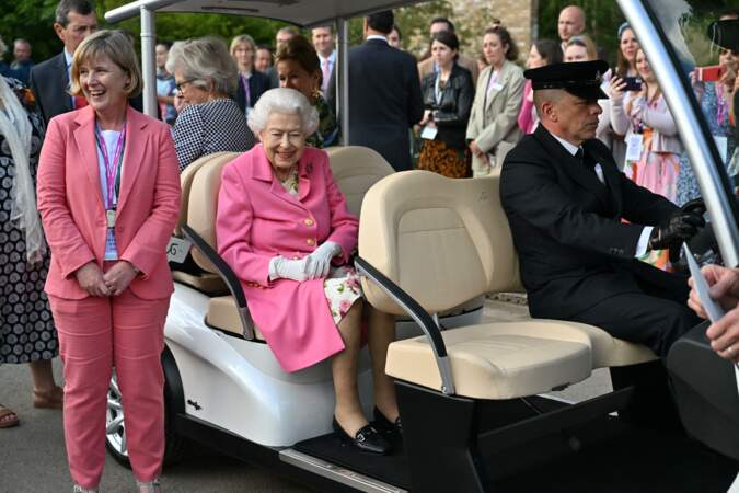 La reine Elizabeth II de rose vêtue assiste en voiturette de golf à l'exposition florale "RHS Chelsea Flower Show" au Royal Hospital à Londres, le 23 mai 2022.