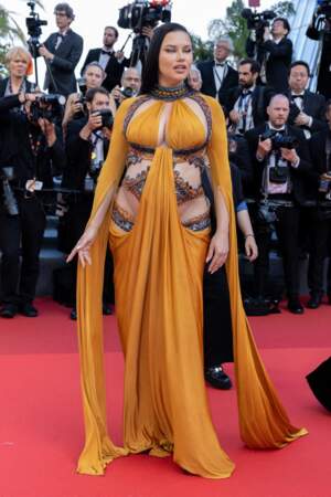 Adriana Lima a dévoilé son baby bump dans une robe vaporeuse cut out signée Nicolas Jebran pour la montée des marches du film « Elvis » lors du 75ème Festival International du Film de Cannes, le 25 mai 2022.