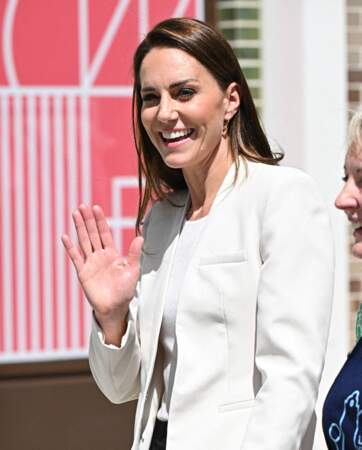 Cheveux longs bruns lachés, veste longue de blazer crème, Kate Middleton tout sourire à Londres le 8 juin 2022.