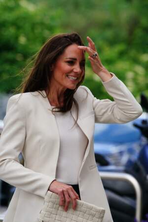 Kate Middleton coiffe ses cheveux longs en side-hair. Cette veste de blazer blanc crème fait ressortir son teint lumineux et le brun de sa chevelure.