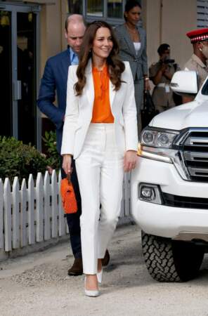 Kate Middleton porte un ensemble de tailleur blanc qu'elle rehausse d'une teinte plus flashy, le orange à l'occasion de son voyage officiel en Jamaïque, le 23 mars 2022.