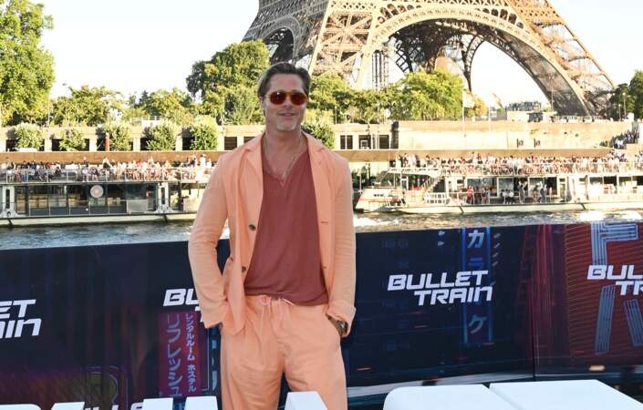 Brad Pitt pose, décontracté et souriant, devant la Tour Eiffel, depuis un bateau-mouche le 16 juillet 2022, en promotion pour "Bullet Train"