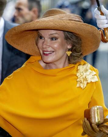 La reine Mathilde de Belgique porte une broche sur sa robe orange, le 21 juillet 2022. 