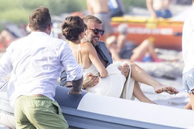 En grand gentleman, David Beckham prend sa femme dans les bras pour monter dans l'annexe du yacht pour éviter que sa belle ne mettre les pieds dans les algues, à Saint-Tropez, le 23 juillet.