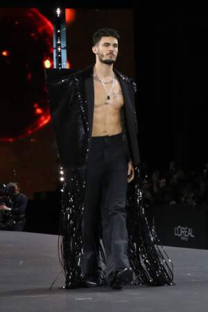 Baptiste Giabiconi foule le podium du défilé L'Oréal Paris avec une longue veste à sequin, le 2 octobre 2022. 