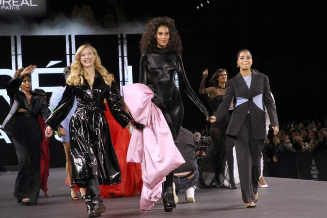 Cindy Bruna en longue robe noire et détail rose aux côtés de Camille Razat et Leïla Bekhti, le 2 octobre 2022. 