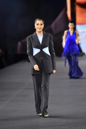 Leïla Bekhti défile pour la marque L'oréal avec un ensemble de costume découpé et à rayures, le 2 octobre 2022. 