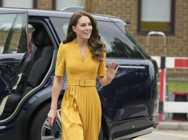 Kate Middleton porte une longue robe plissée jaune moutarde lors d'une visite à la maternité du Royal Surrey County Hospital, le 5 octobre 2022. 
